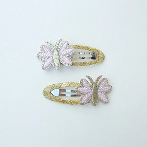 Detail of glittery pink embroidered butterfly hair clips with gold metal BB clip base