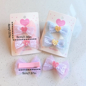 Detail view of heart-patterned lace bow hair clips in pink, blue, and purple colors