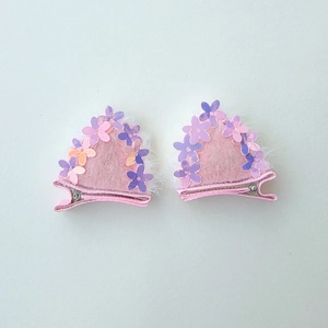 Detail view of pink glitter cat ear hair clips with sequin flowers and white fur trim