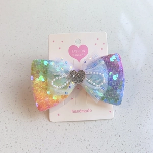 Détail d'un nœud papillon arc-en-ciel à paillettes avec perles et décor de cœur