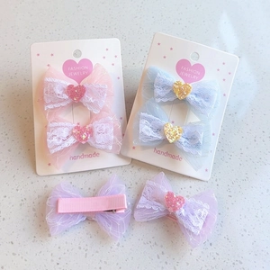 Detailed view of handmade lace bow hair clips with glitter hearts and pink ribbon duckbill clips