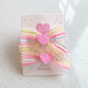 Set mit zwei rosa Organza-Regenbogen-Haarspangen mit Glitzerherzen auf Karte