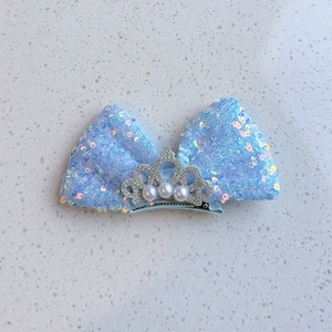 Détail de la pince à cheveux noeud bleu clair à paillettes avec couronne et perles