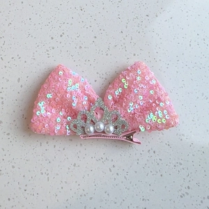 Détail de la pince à cheveux nœud à paillettes roses avec couronne et accents de perles
