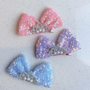 Détail de trois barrettes nœuds à paillettes avec couronne et perles nacrées