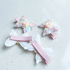 Detailed view of sequin butterfly hair clips with pink fabric roses and metal alligator grips