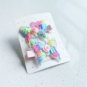 Detailed view of handmade sequined butterfly hair clips with rose on display card