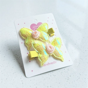 Set of two yellow embroidered butterfly hair clips with pearls on a cardboard display card