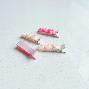 Détail de barrettes à roses en ruban de satin rose et beige avec pince en métal