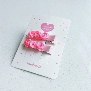 Vue détaillée de deux barrettes roses en soie faites à la main sur leur carte