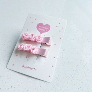 Gros plan de pinces à cheveux roses en satin faites à la main pour filles sur carton