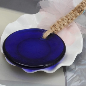 Close-up of blue glass evil eye pendant with rustic jute rope on a textured white plate