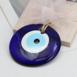 Detailed close-up of blue glass Evil Eye pendant with a soft pink decorative flower