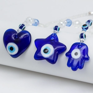 Detailed view of evil eye charms in heart, star, and hamsa shapes with blue beads