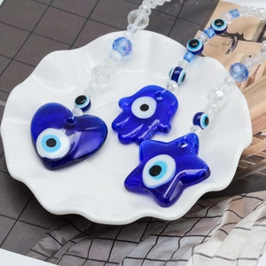 Detail view of Evil Eye charms in heart and Hamsa shapes with blue crystal beads