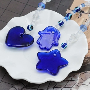 Blue heart, star and Hamsa hand evil eye pendants in white ceramic bowl