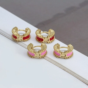 Close-up of pink and red enamel C-shape hoop earrings with vintage gold textured details