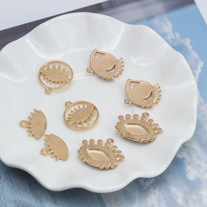 Ciondoli dorati malocchio per creazione gioielli fai-da-te su un piatto di ceramica