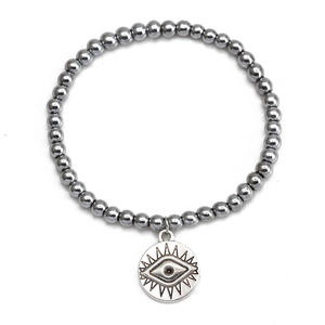 Macro detail of hematite beaded bracelet featuring a silver Evil Eye charm and lucky amulet