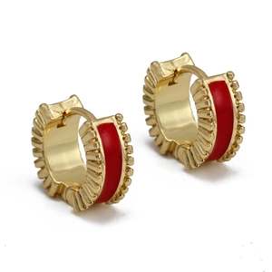 Detailed close-up of golden C-shaped huggie earrings with red enamel and radial texture