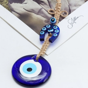 Dettaglio del ciondolo Evil Eye in vetro blu con corda di iuta su sfondo bianco puro