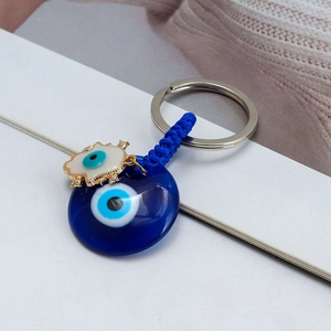 Macro shot of blue glass evil eye pendant with enamel charm and blue braided rope