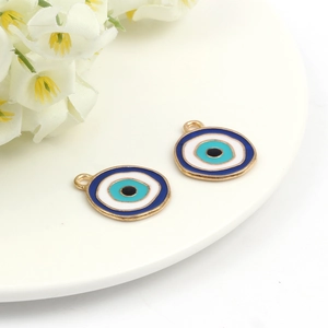 Close-up of blue evil eye alloy charms for DIY necklace making on white tray with flower