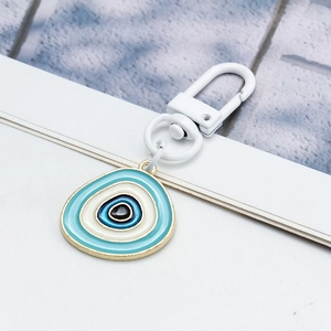Dettaglio del ciondolo occhio blu con bordo dorato e moschettone bianco lucido