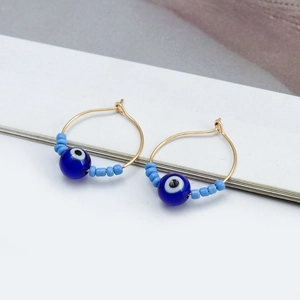 Detailed close-up of handmade gold hoop earrings with evil eye beads and colorful seed beads