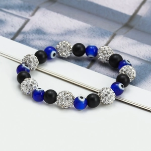 Macro shot of blue evil eye beads and black matte round beads on the woven bracelet