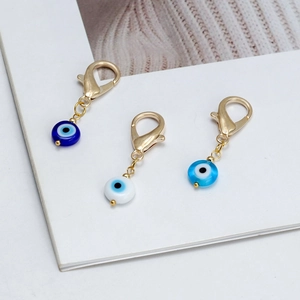 Détail des pendentifs œil maléfique en verre bleu et blanc avec fermoirs mousquetons dorés