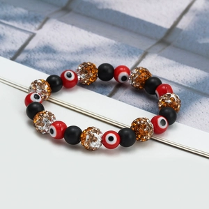 Detail showing red evil eye beads, matte black beads and rhinestone accents on a woven bracelet