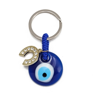 Detail of blue evil eye keychain with golden horseshoe and sparkling white rhinestones