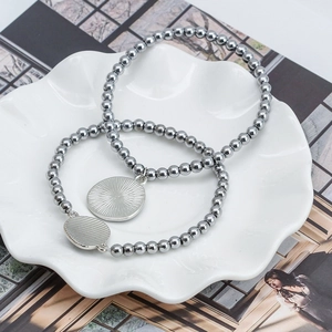 Silver bead bracelets with evil eye pendants set in a ceramic dish on a magazine