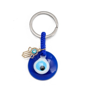 Close-up of golden Hamsa hand and blue glass Evil Eye charm on key ring holder