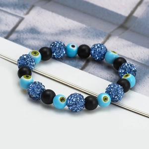 Macro detail of blue crystal beads and evil eye charm on woven elastic bracelet