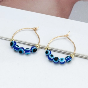 Detailed macro view of colorful evil eye beads and gold stars on hoop earrings