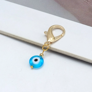 Détail d'un fermoir mousqueton doré avec pendentif œil bleu en verre sur un porte-clés chic