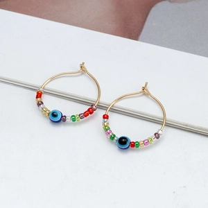 Detail of bohemian gold hoop earrings with evil eye beads and colorful glass seed beads
