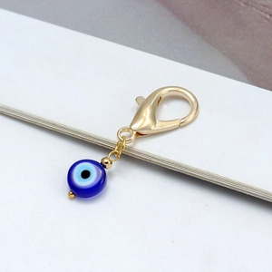 Détail du fermoir mousqueton doré avec perle en verre œil bleu sur porte-clés chic