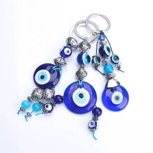 Detailed close-up of blue glass Evil Eye charms with silver metal beads on a keychain set