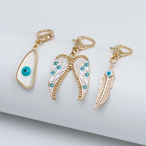 Vue détaillée de pendentifs œil bleu avec breloques ailes et plumes dorées sur socle