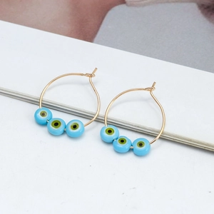 Gold hoop earrings with blue evil eye beads and colorful star drop charms