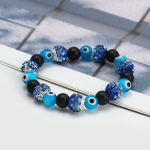 Detailed macro view of the evil eye beads and blue rhinestone charms on the bracelet
