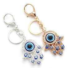 Detailed macro view of gold and silver Hamsa Hand keychains with Evil Eye enamel charms