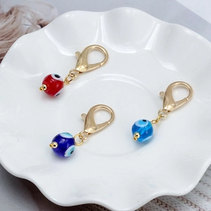 Trois pendentifs œil maléfique en verre avec fermoirs dorés et perles bleues