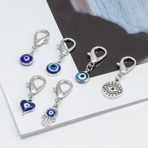 Close-up of 6 Evil Eye and Hamsa pendants with polished silver finish and blue enamel