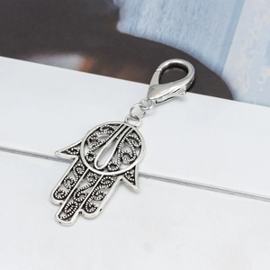 Close-up of vintage Hamsa hand pendant with intricate hollow carvings and lobster clasp