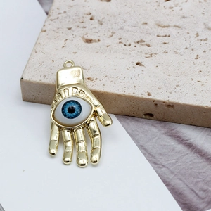 Macro del ciondolo a mano di Hamsa dorata con occhio blu su sfondo in pietra naturale