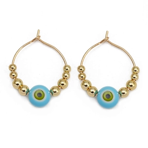 Detail view of gold beaded hoop earrings with light blue evil eye charms on white background